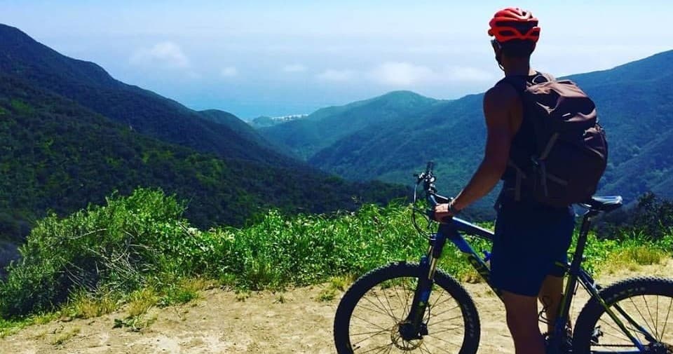 Mountain biker overlooking green valley on scenic LA ridge