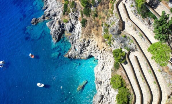 Aerial view of terraced coastal path and boats in clear blue water