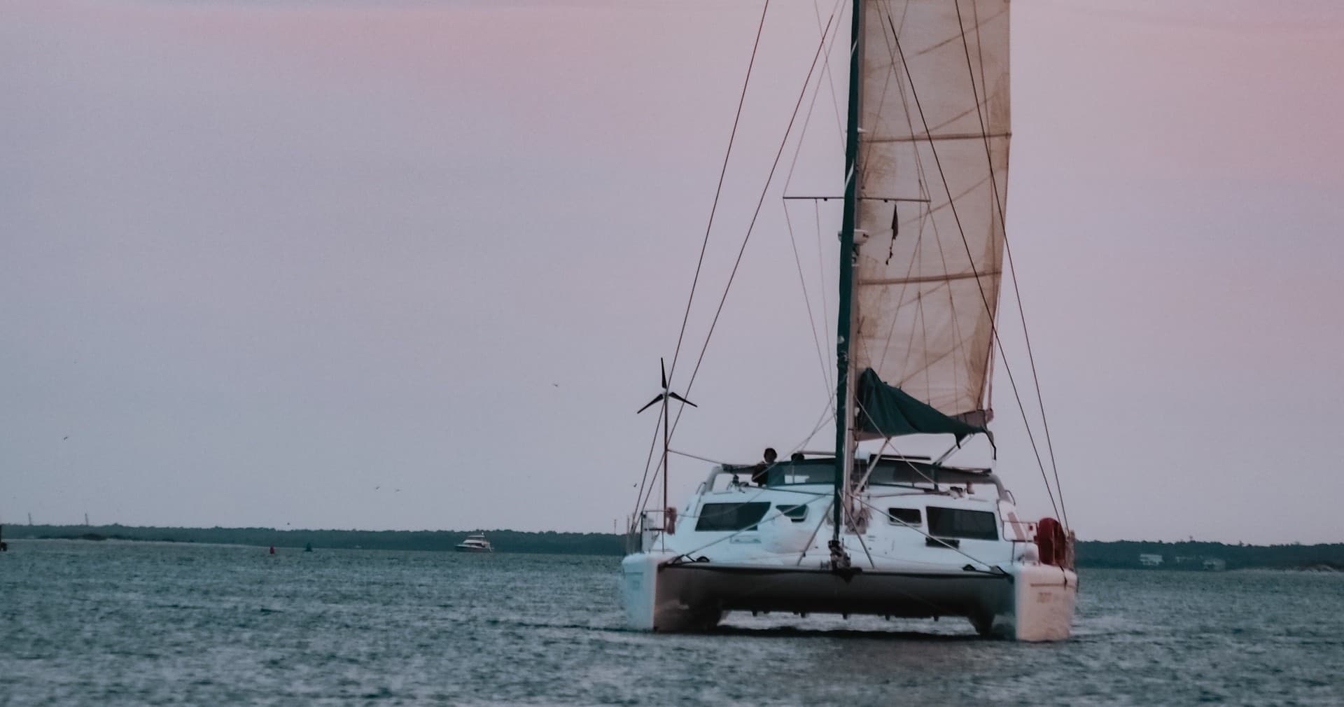 Sailboat bow cutting through calm sea at dusk, ocean view
