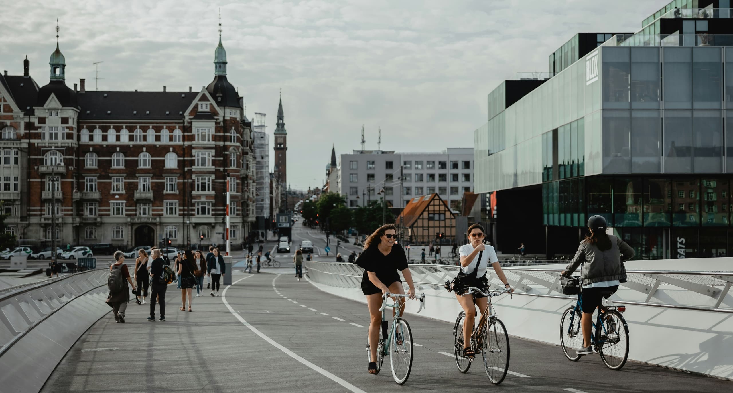 Cyclists riding across urban bridge by waterfront buildings