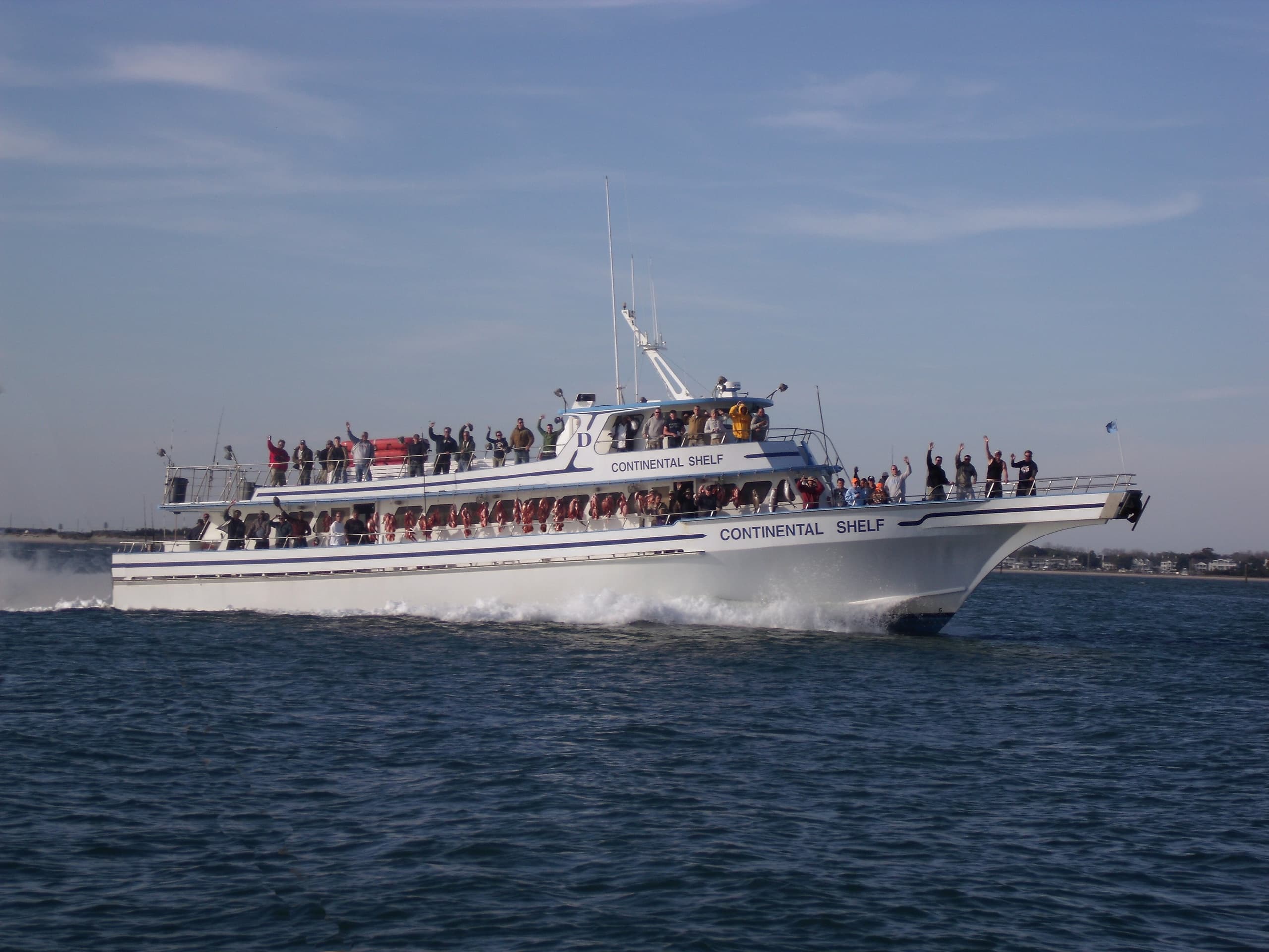 Charter fishing boat underway with anglers on deck in open ocean