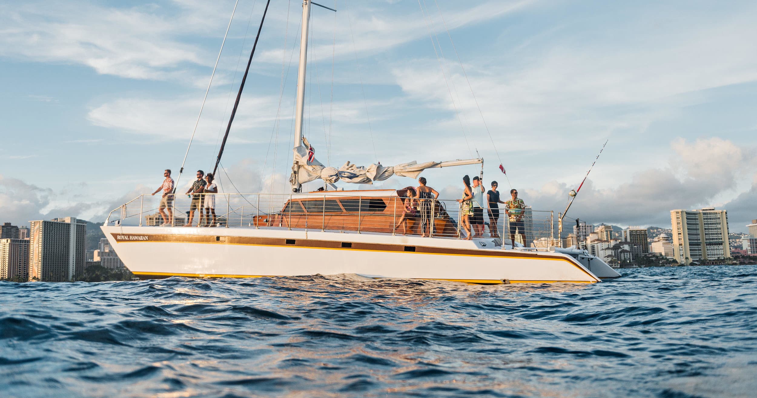 Group aboard catamaran sailing on open ocean near shore