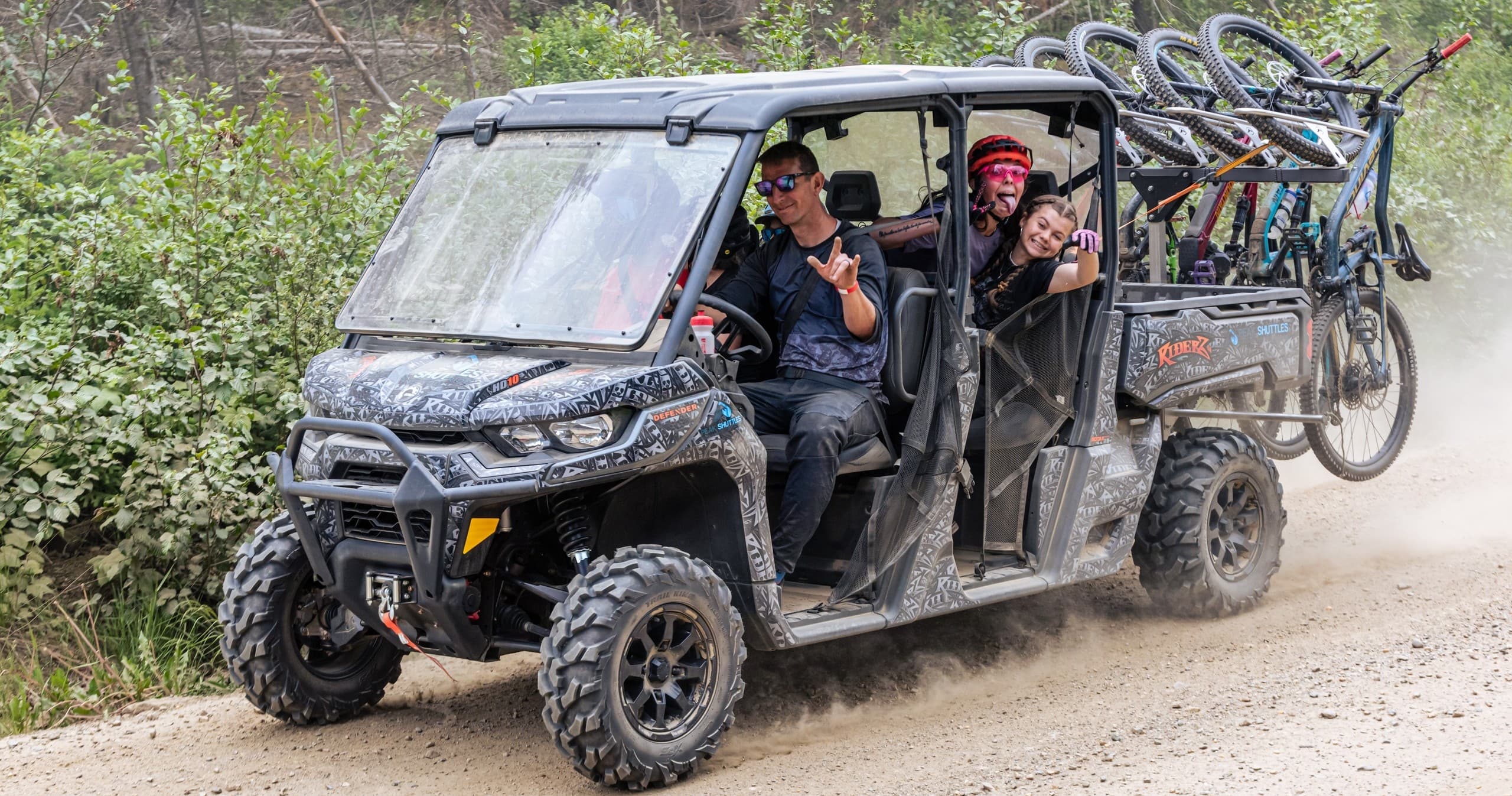 Off-road UTV carrying mountain bikes on dirt trail with riders