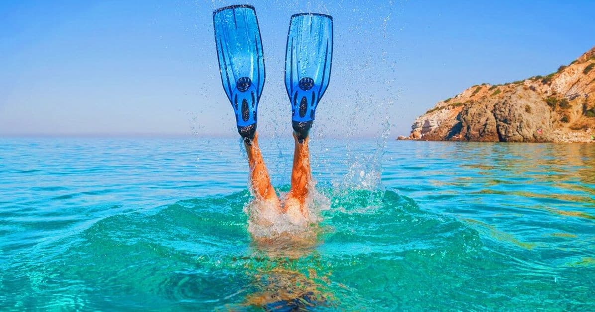 Snorkeler kicking with blue fins near rocky Mazatlán shoreline