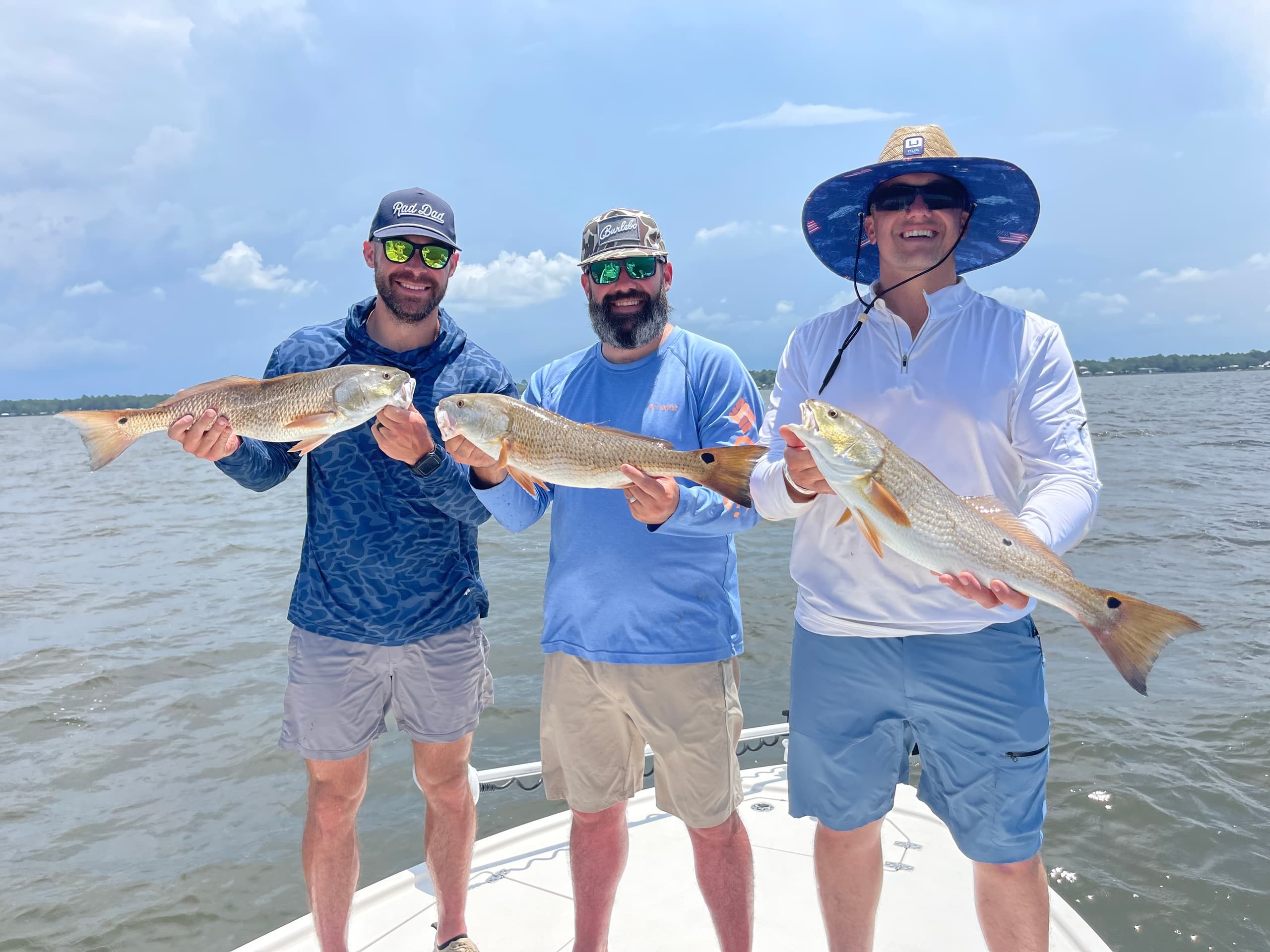 Three anglers showing redfish catch on backwater bay boat