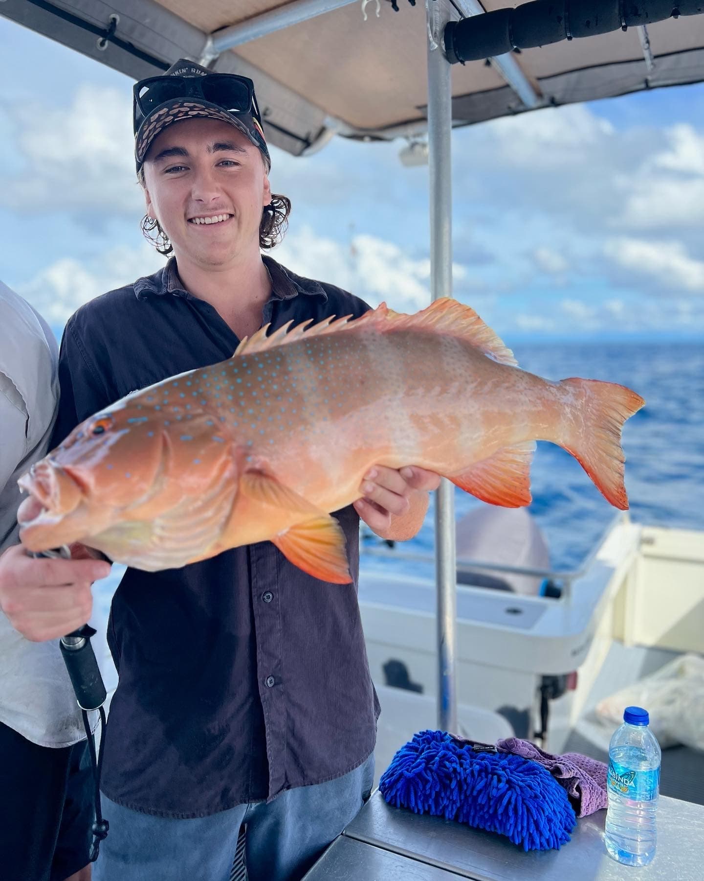 Angler holding reef grouper on deck during tropical offshore fishing trip