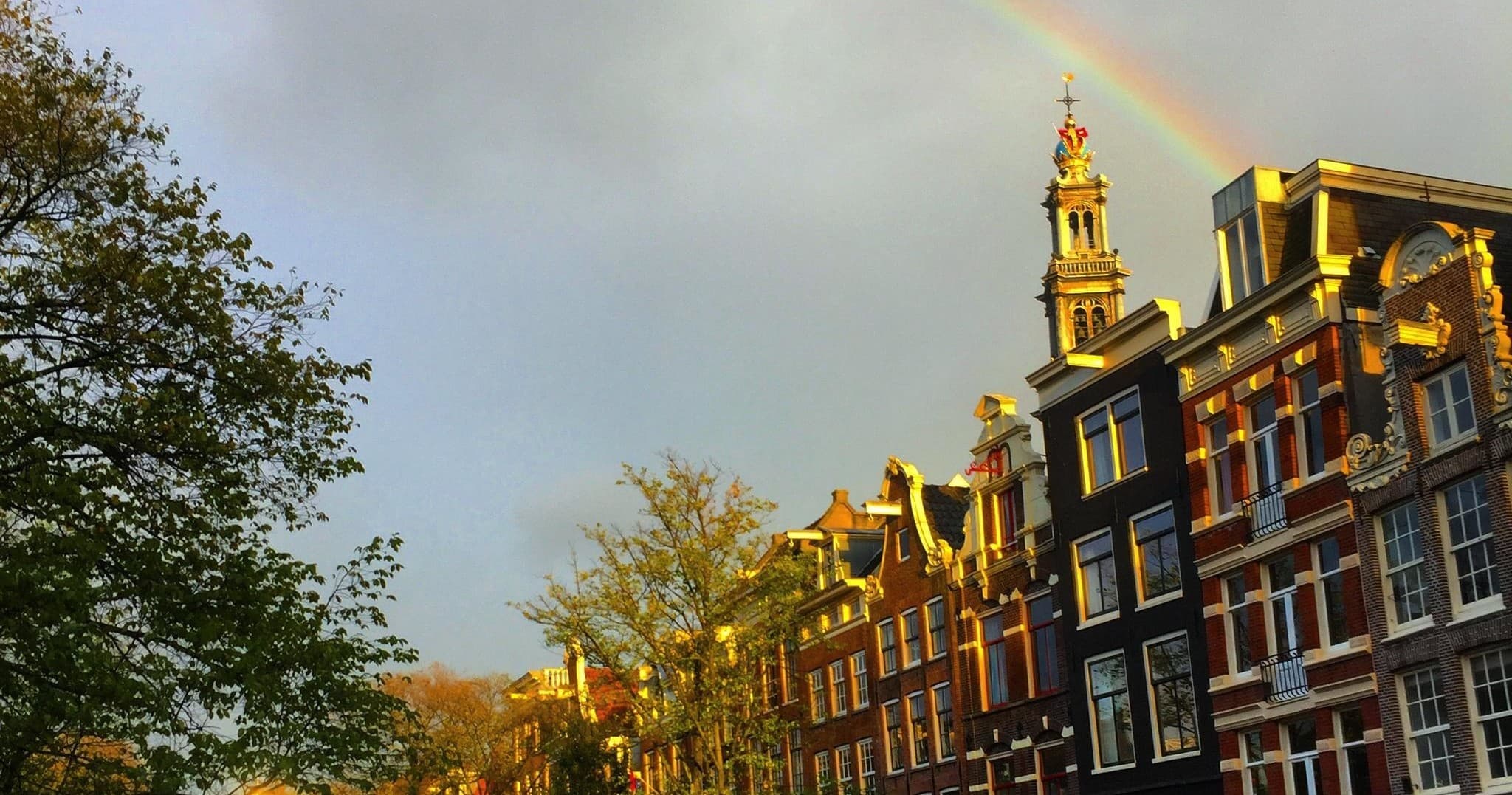 Amsterdam canal skyline with rainbow over historic canal houses