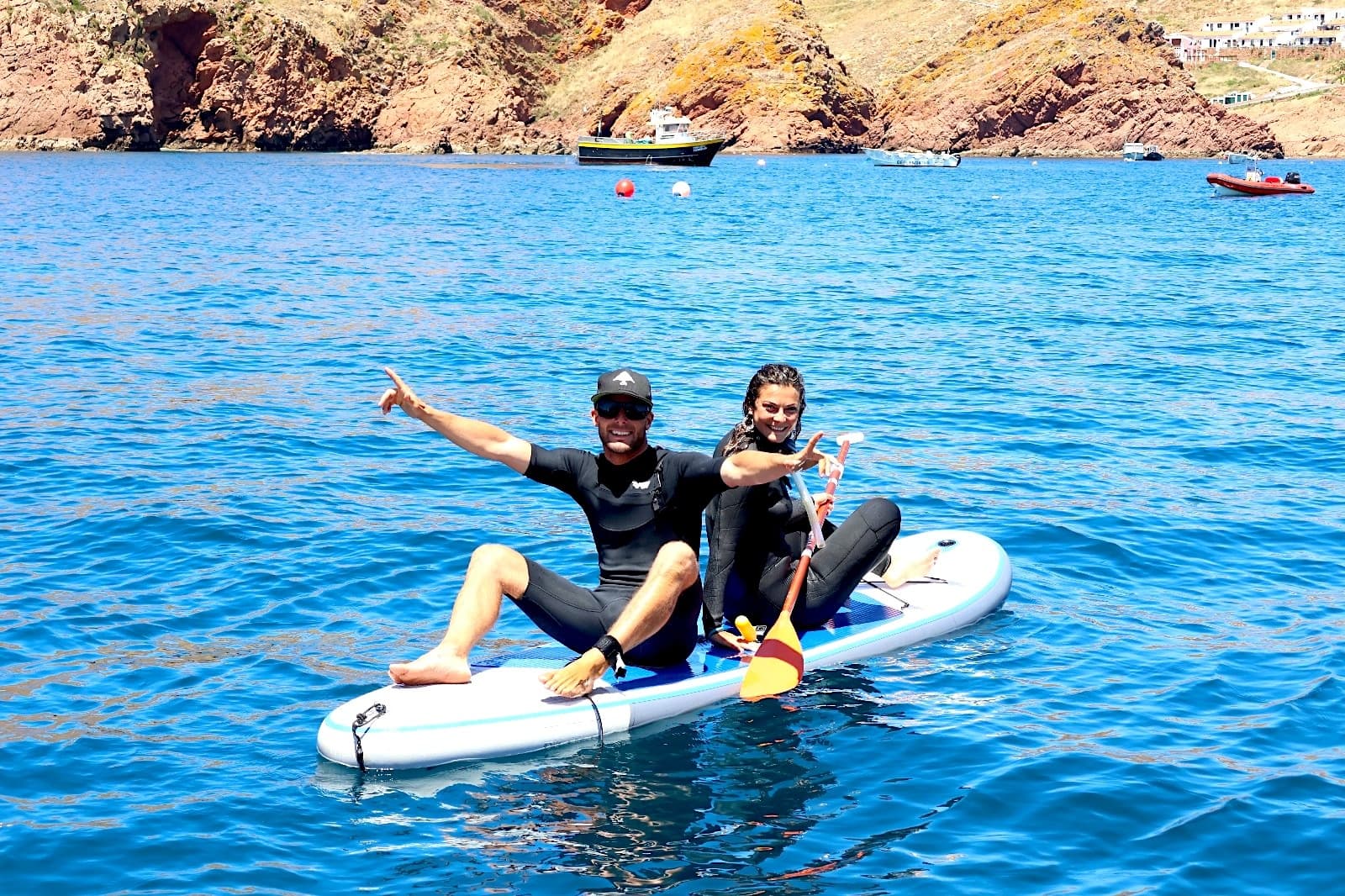 Two paddlers on inflatable SUP enjoying clear blue coastal waters