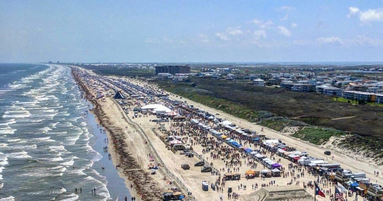 Aerial beach crowd and festival tents along shoreline