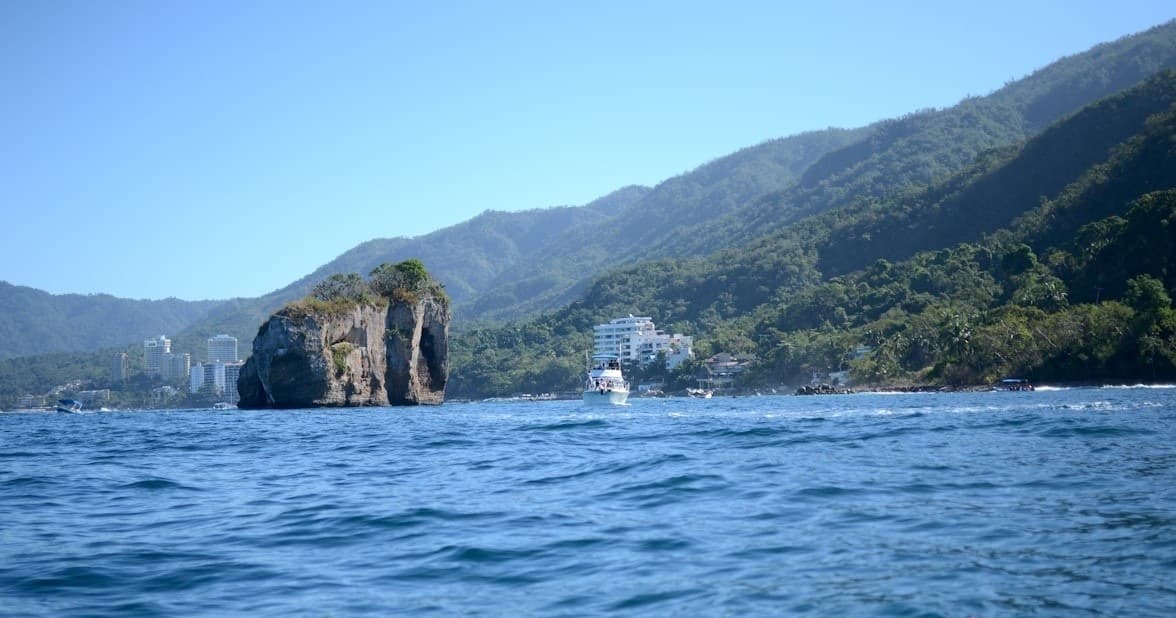 Coastal cliffs and sea view with sailboat near rugged shoreline