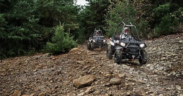 UTVs navigating rocky hillside trail, rugged off-road terrain ride