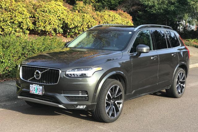 Volvo SUV parked roadside near vineyard hedgerow for tour