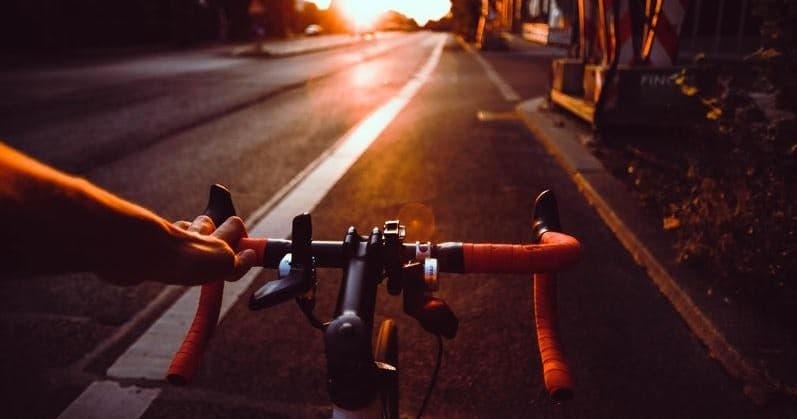 Road bike handlebars at sunset on open asphalt road