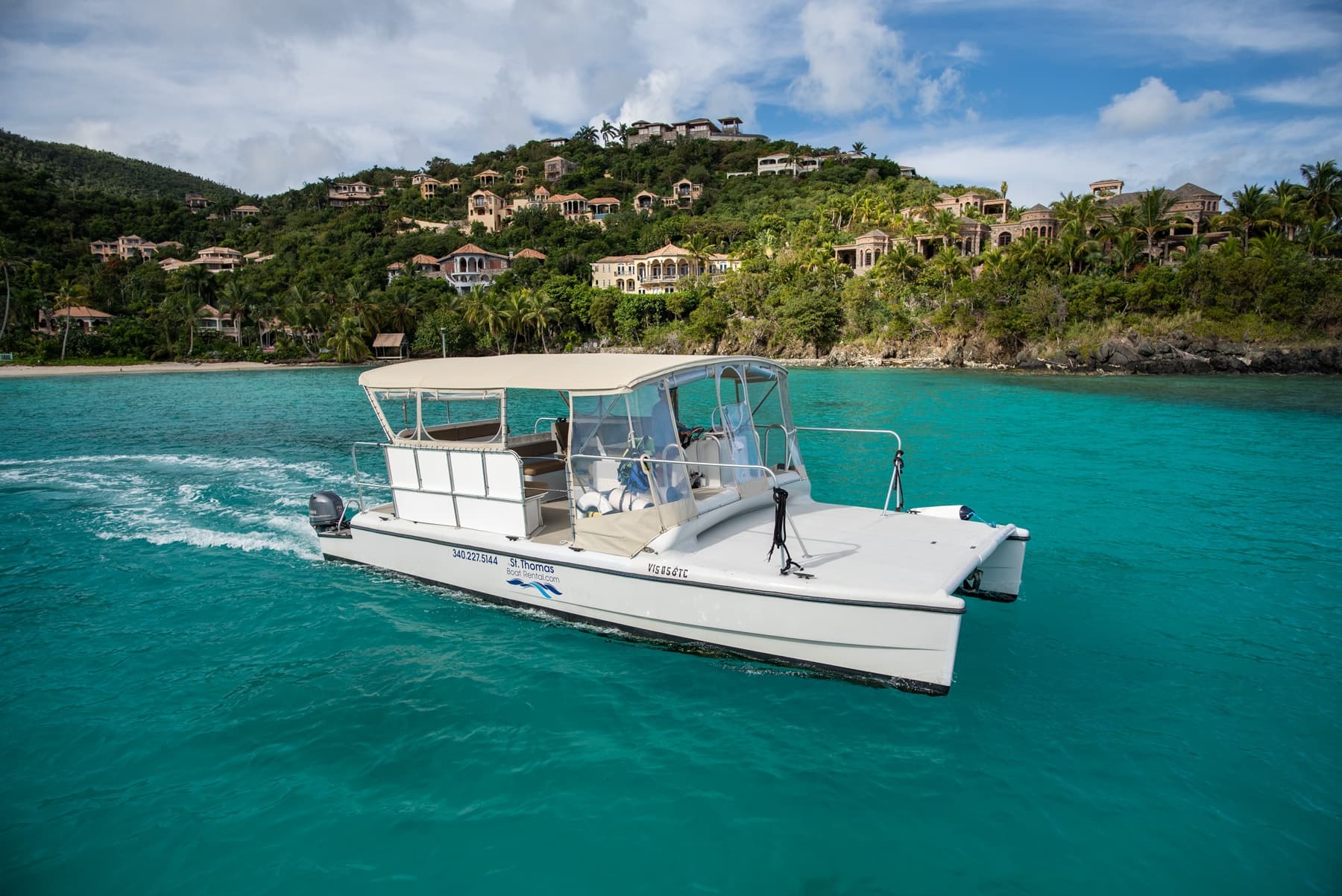Sightseeing boat cruising clear turquoise sea past hillside villas