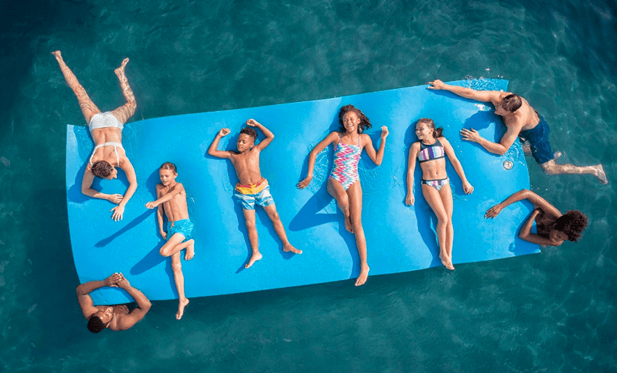 Group sunning and lounging on a giant float mat in clear lake