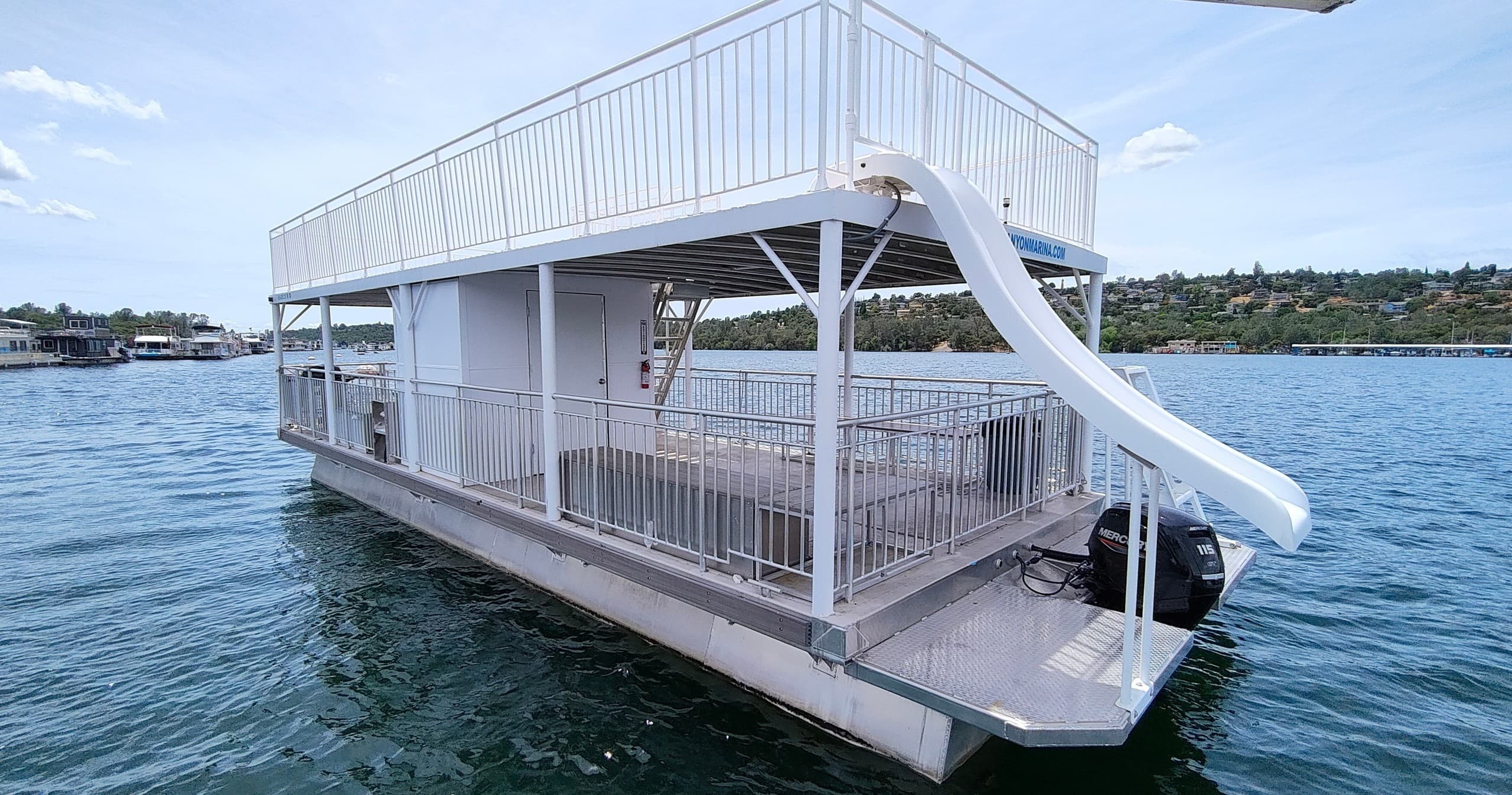 Houseboat with waterslide docked on calm blue lake