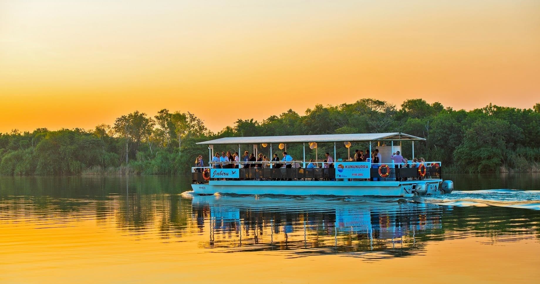 Sunset river cruise boat gliding past mangroves in Kununurra