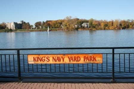 Riverside park railing with King's Navy Yard Park sign and water view