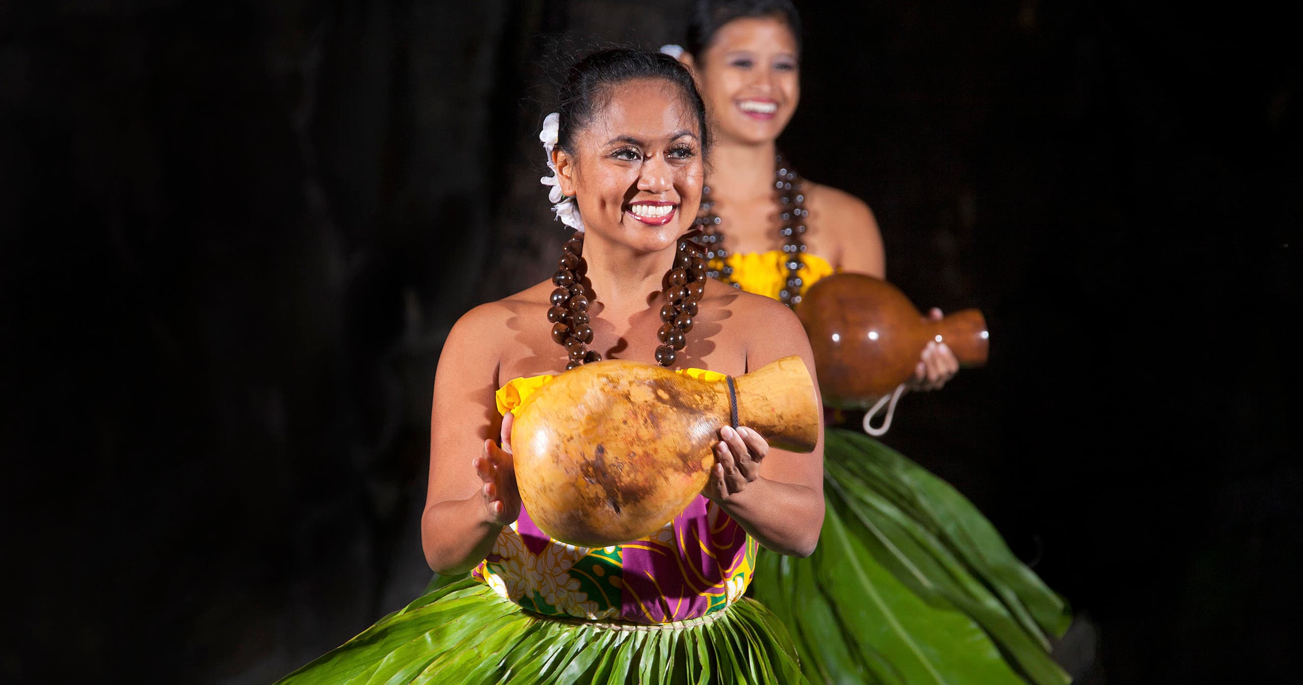 Solo hula dancer holding gourd at Hawaiian luau on Maui beach