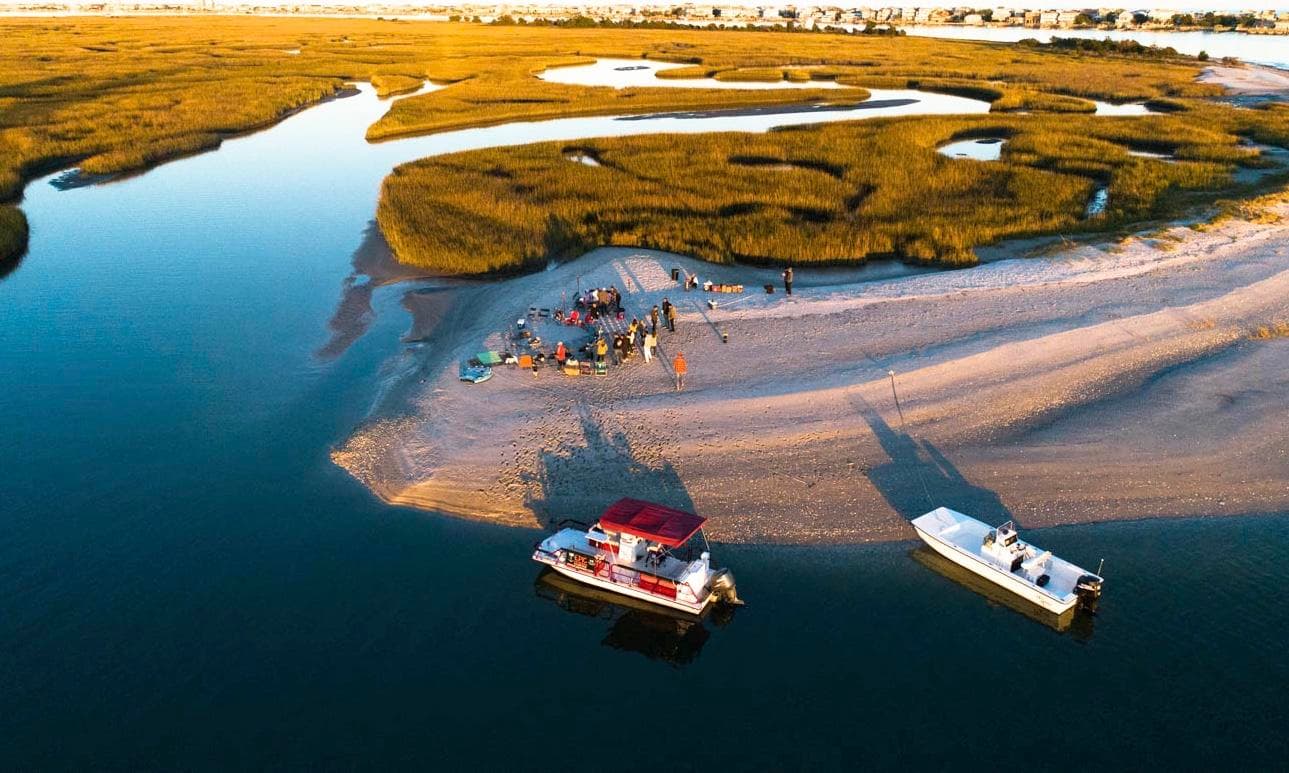 Aerial view of boats near coastal marsh and sandy inlet