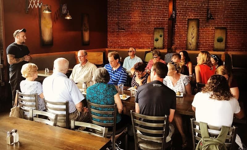 Indoor group dining on guided food tour in brick-walled Asheville restaurant
