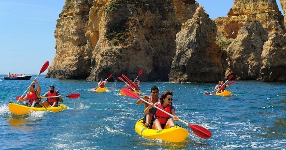 Kayakers paddling near Lagos rocky sea cliffs, coastal tour