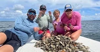 Family on boat with large haul of clams during coastal shelling trip