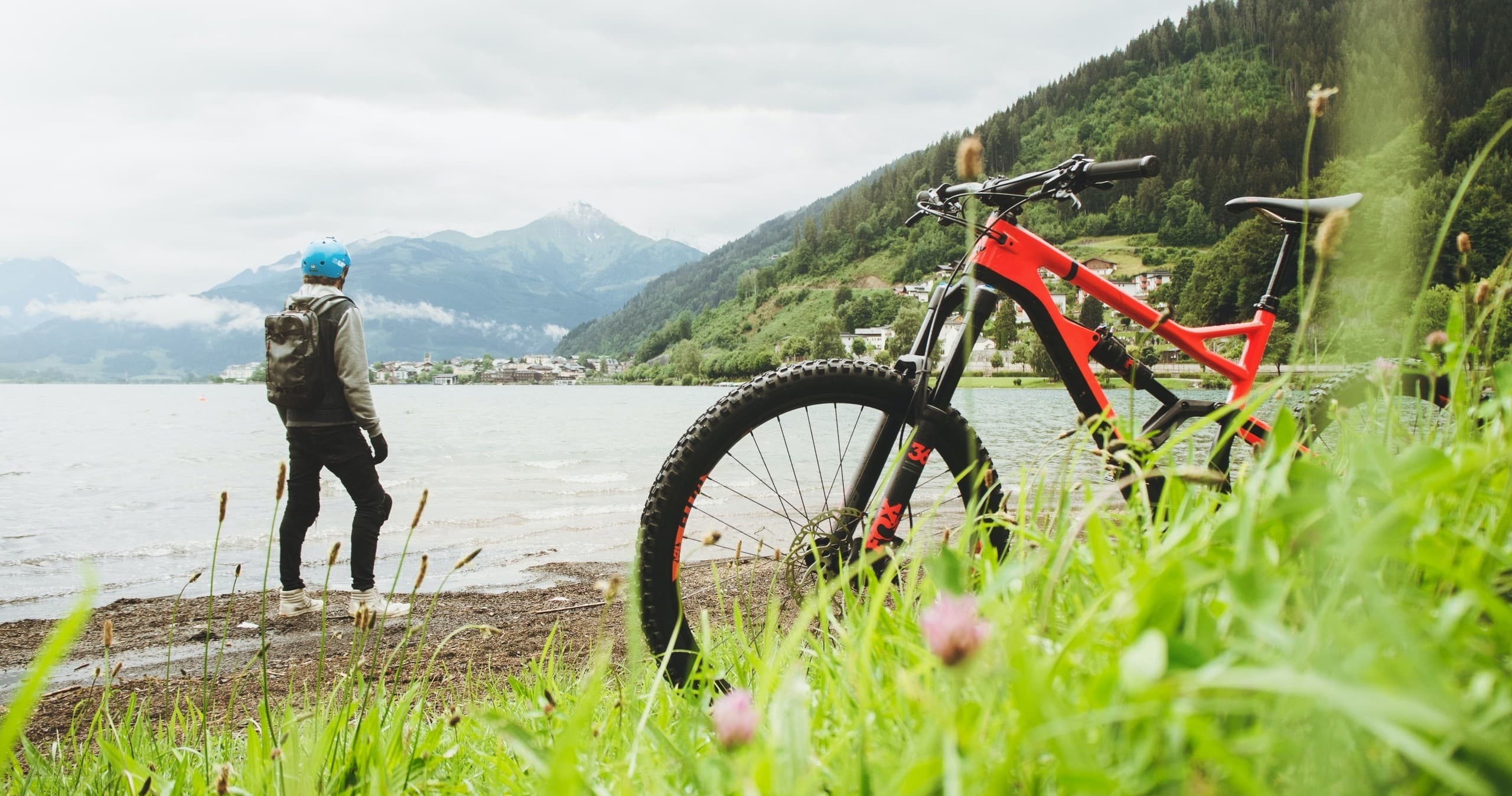 Mountain biker parked lakeside with hiker amid alpine lake scenery