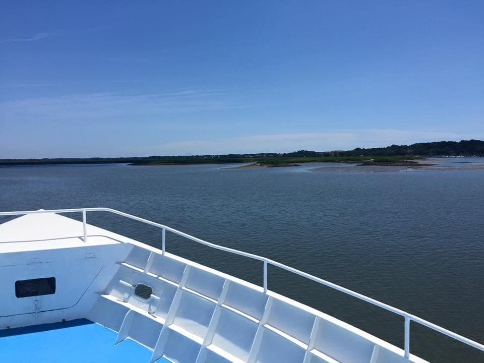 Boat deck overlooking calm coastal waters during sunny cruise