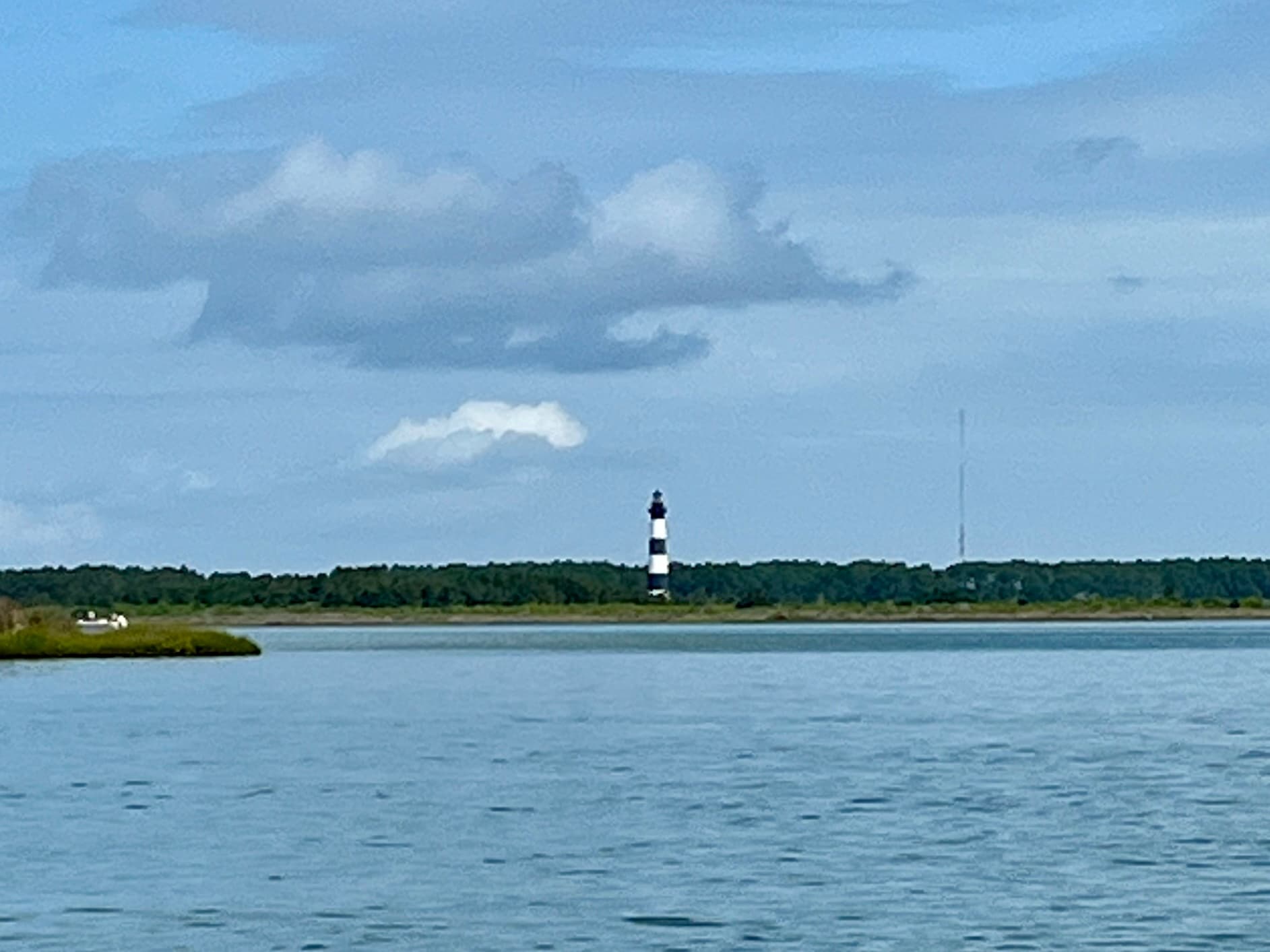 Scenic lighthouse across calm bay, coastal boating vista