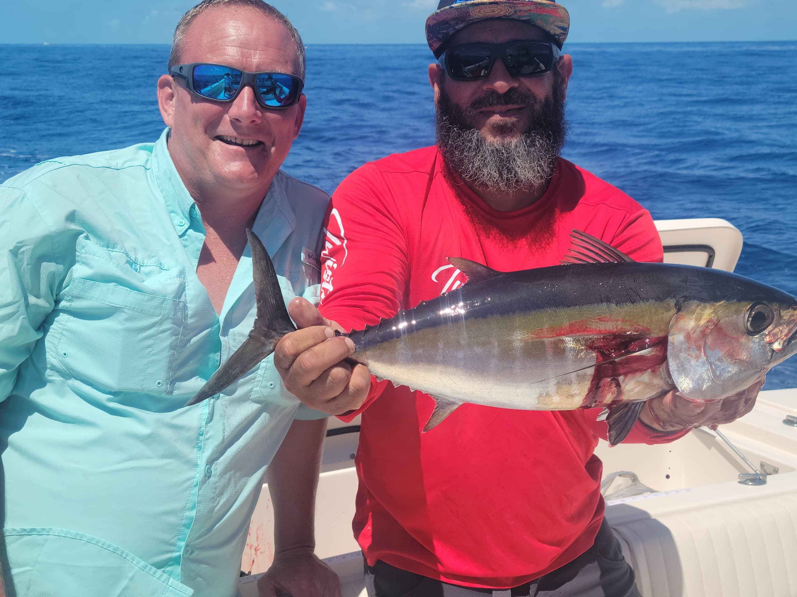 Two anglers holding tuna aboard ocean sportfishing charter trip