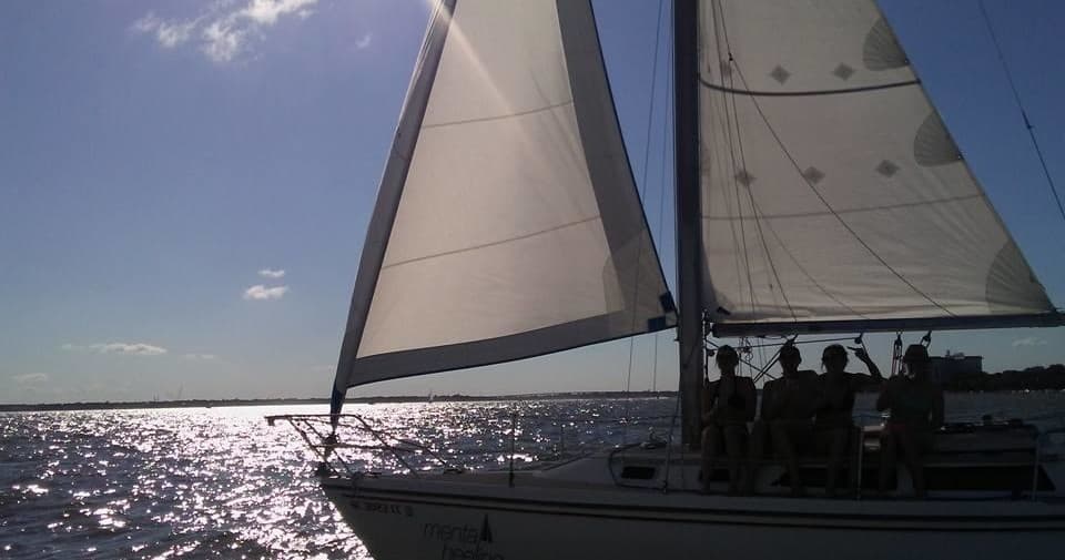 Sailboat with crew under full sails on Charleston coastal waters