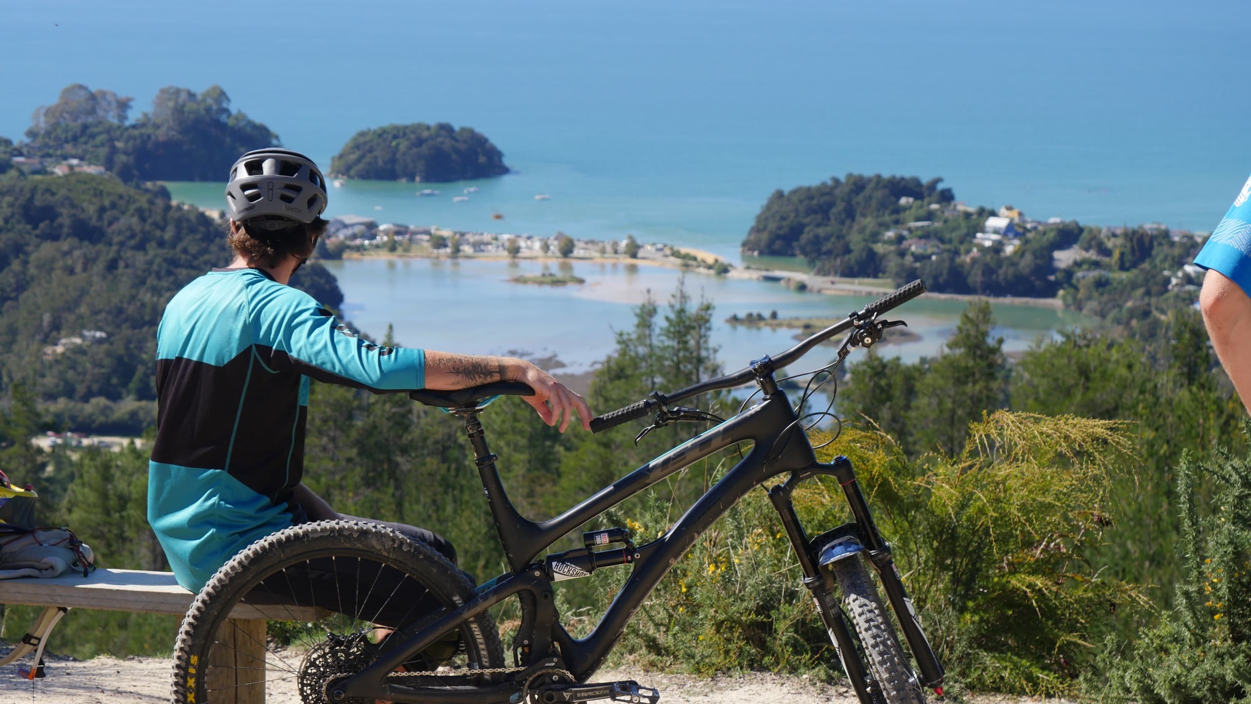 Cyclist overlooking turquoise bay and island views on coastal trail