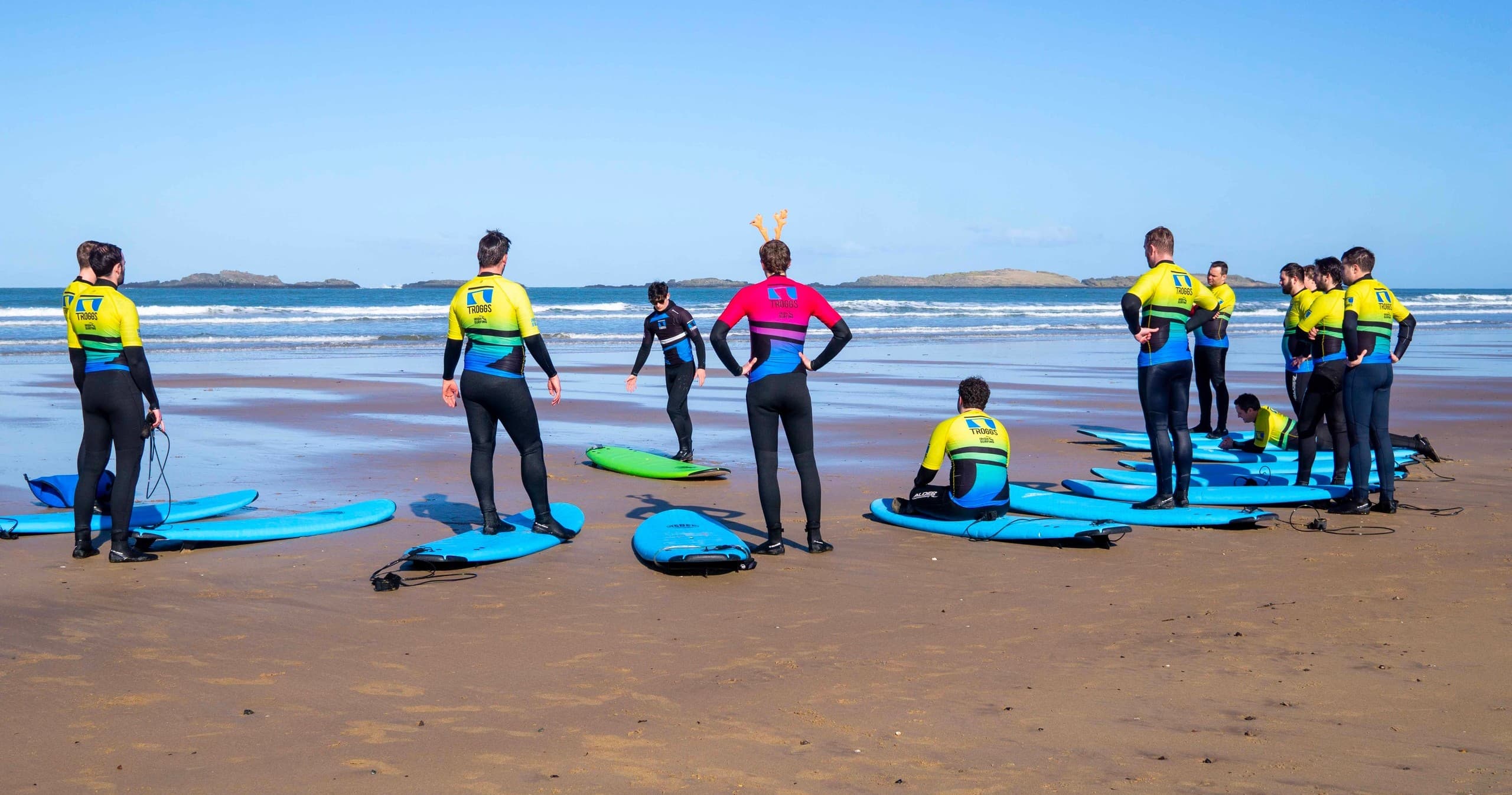 Surf school group on sandy beach prepping for coached lesson