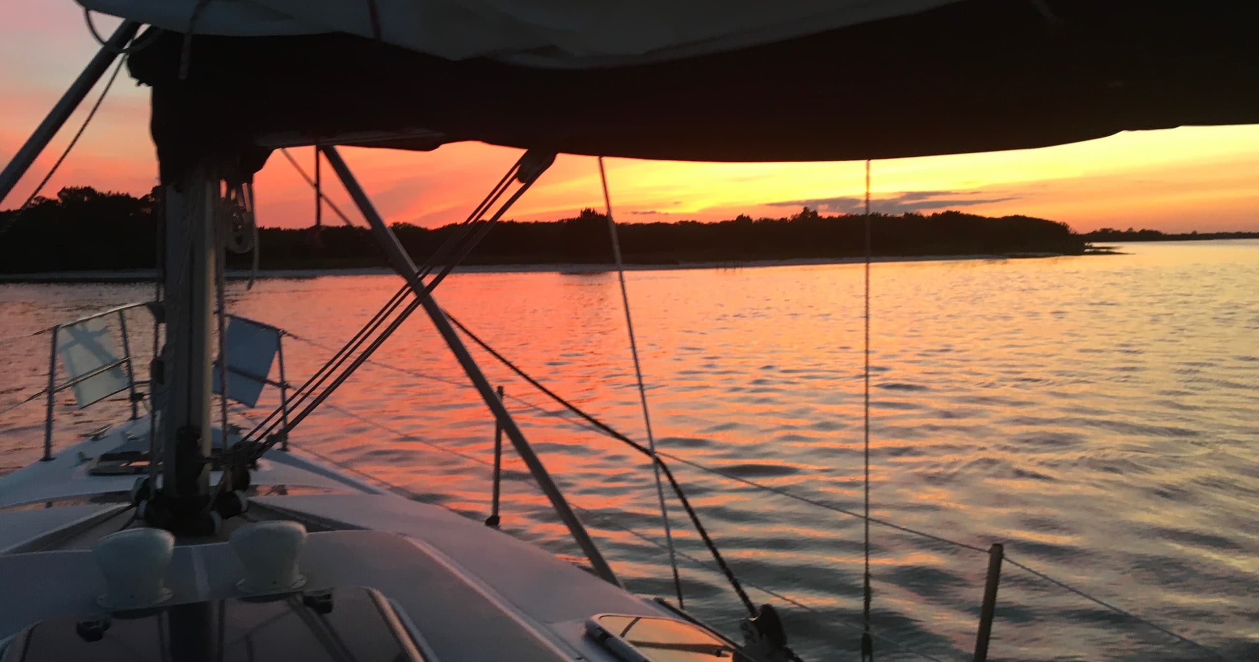 Sailboat cockpit at sunset on calm bay, evening sailing