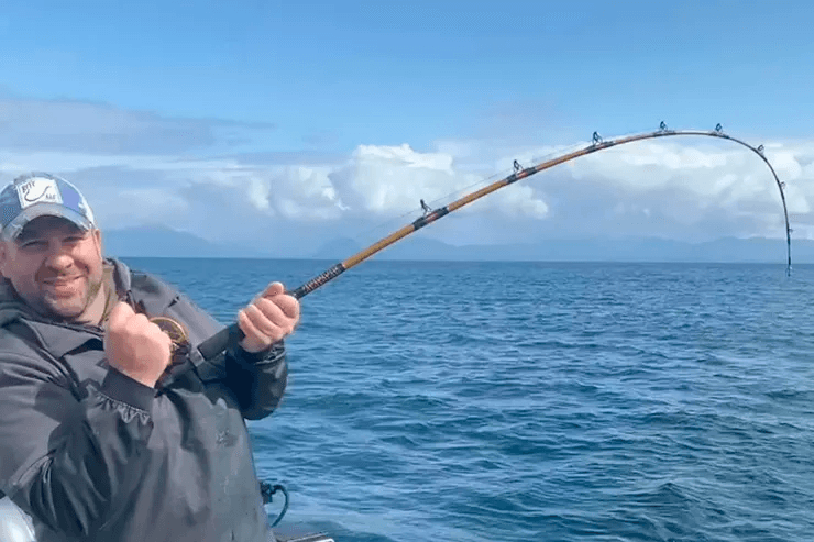 Fisherman reeling on ocean charter boat in open sea