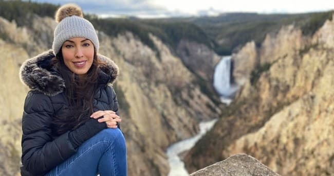 Hiker seated on canyon rim overlooking dramatic waterfall vista