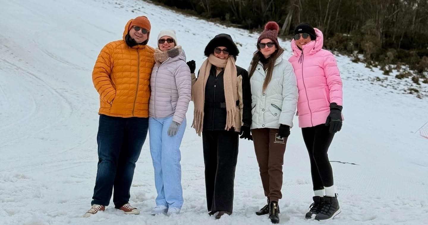Friends in winter jackets posing on snowy mountain trail