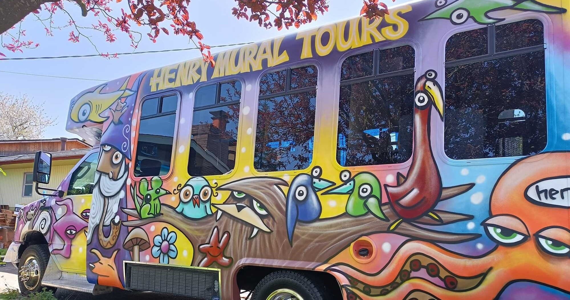 Painted mural tour bus parked under trees during city art tour