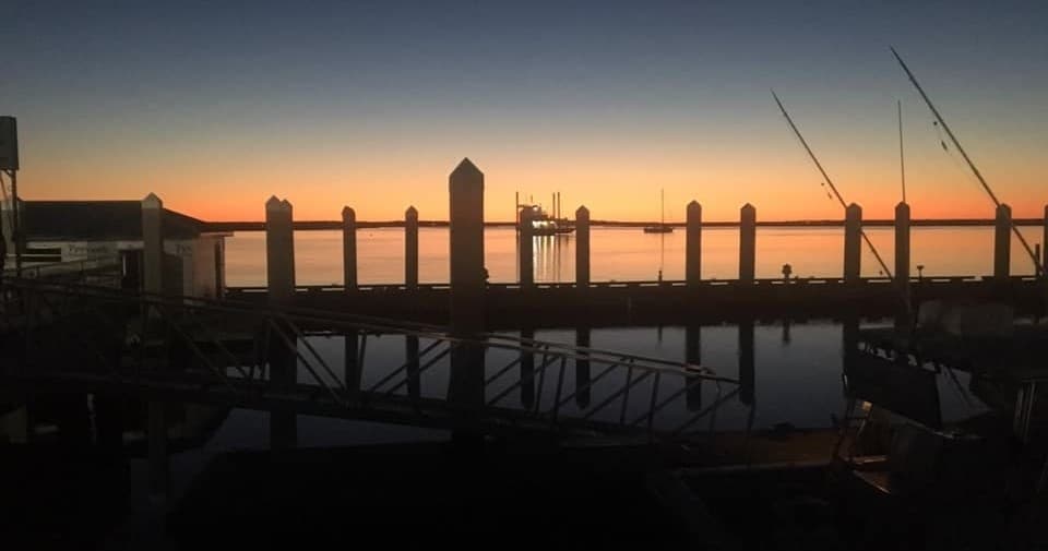 Sunset pier silhouette with fishing rods, dockside angling at dusk