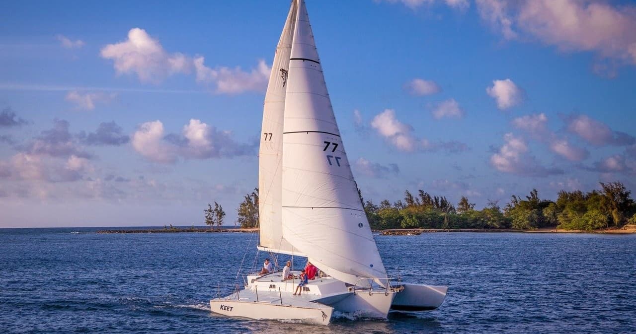 Sailboat tacking offshore under partly cloudy tropical sky