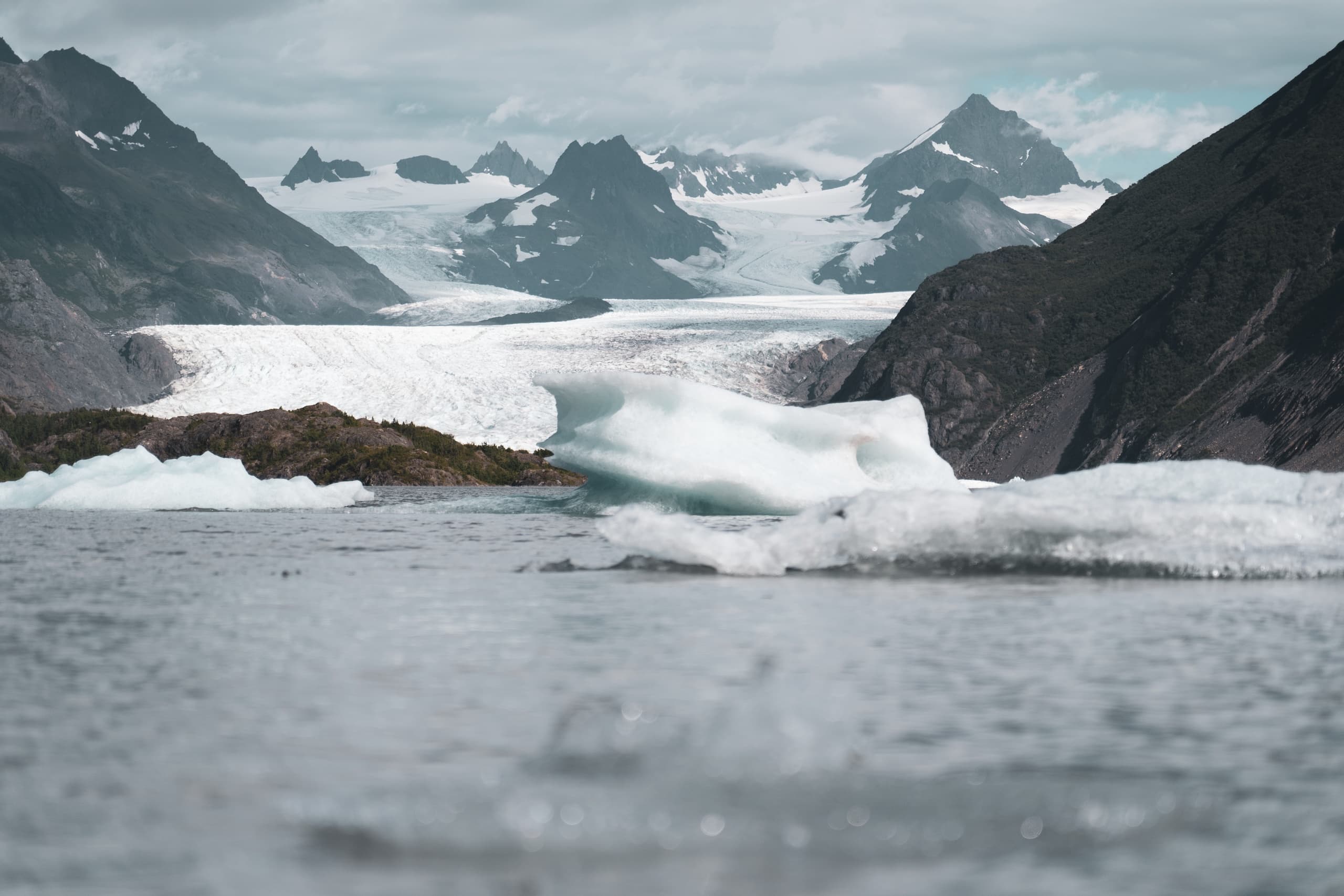 Glacier and ice floes flowing into alpine bay in rugged Alaska