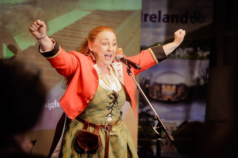 Costumed historical performer on stage delivering lively indoor show