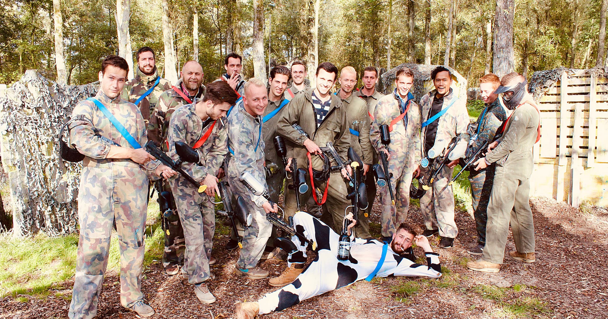 Paintball team posing in woodland field for group game