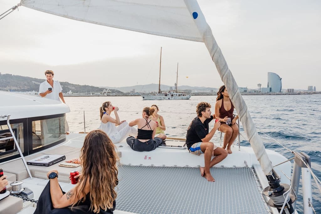Group relaxing on catamaran deck cruising Mediterranean near coast