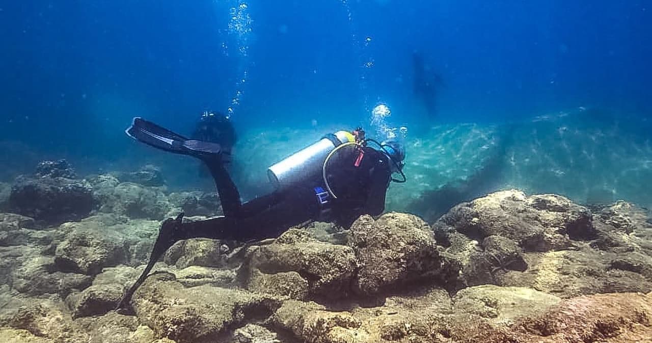 Scuba diver exploring rocky reef in clear tropical water