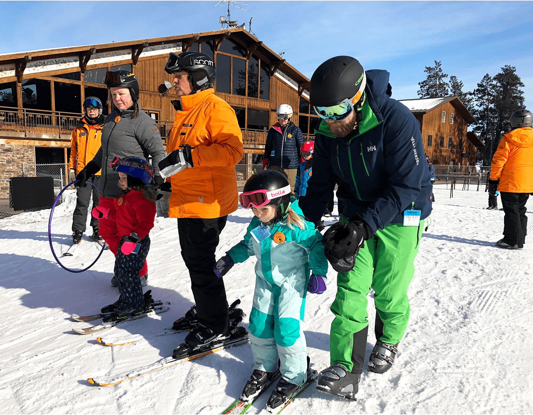 Ski instructors guiding child learner on snowy beginner slope