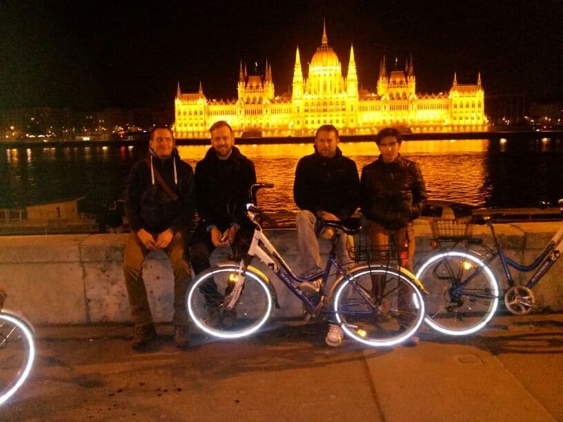 Night bike tour with lit Hungarian Parliament reflections on Danube