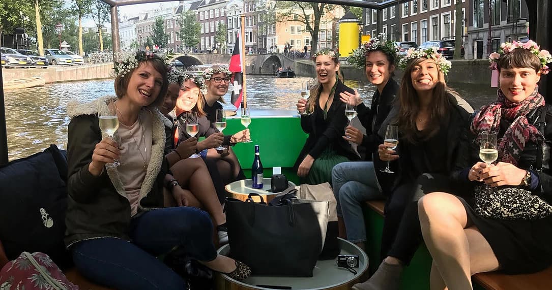 Friends toasting on green-deck boat during Amsterdam canal party