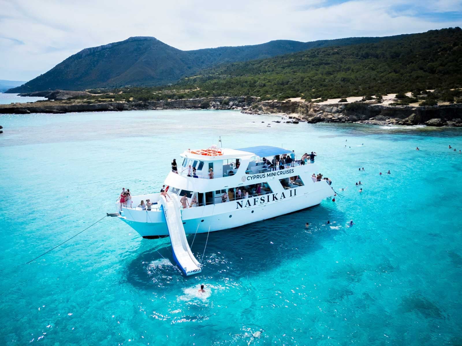 Tour boat with swim platform and passengers enjoying seaside